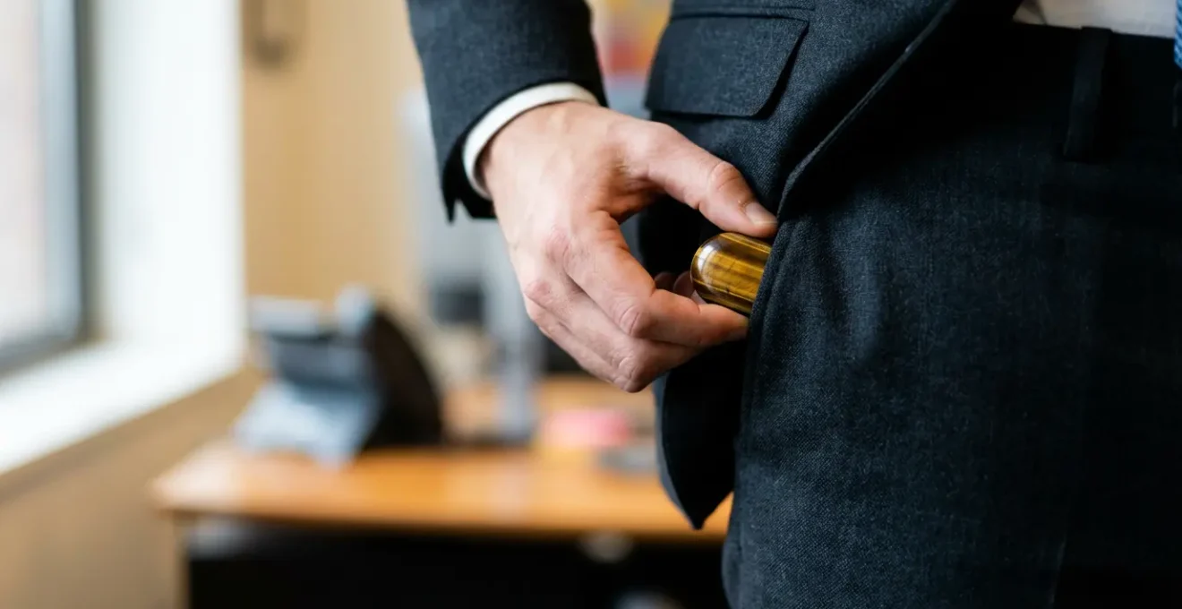 Mano che tiene discretamente una pietra protettiva in tasca durante il lavoro