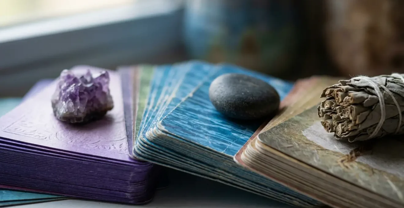 Diversi mazzi di oracoli disposti a ventaglio su tavolo di legno con elementi naturali corrispondenti